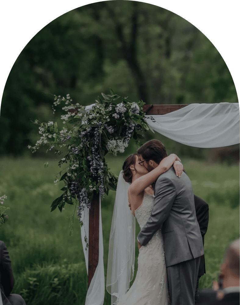 Bride and groom kissing under floral arch