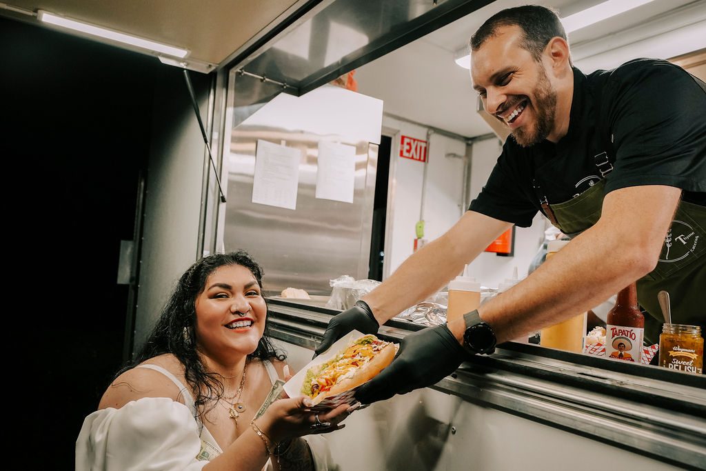 A man serves food through a window to a smiling woman.